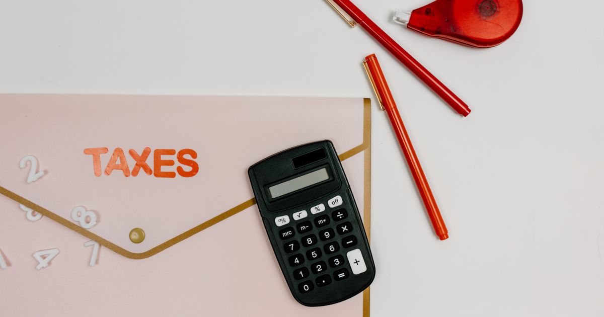 Flat lay image featuring a calculator, pens, and a folder labeled 'TAXES', perfect for finance-related themes.