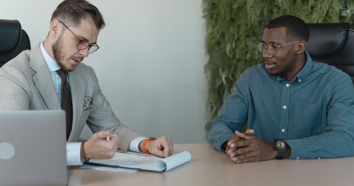 A professional job interview between two men in a modern office environment.