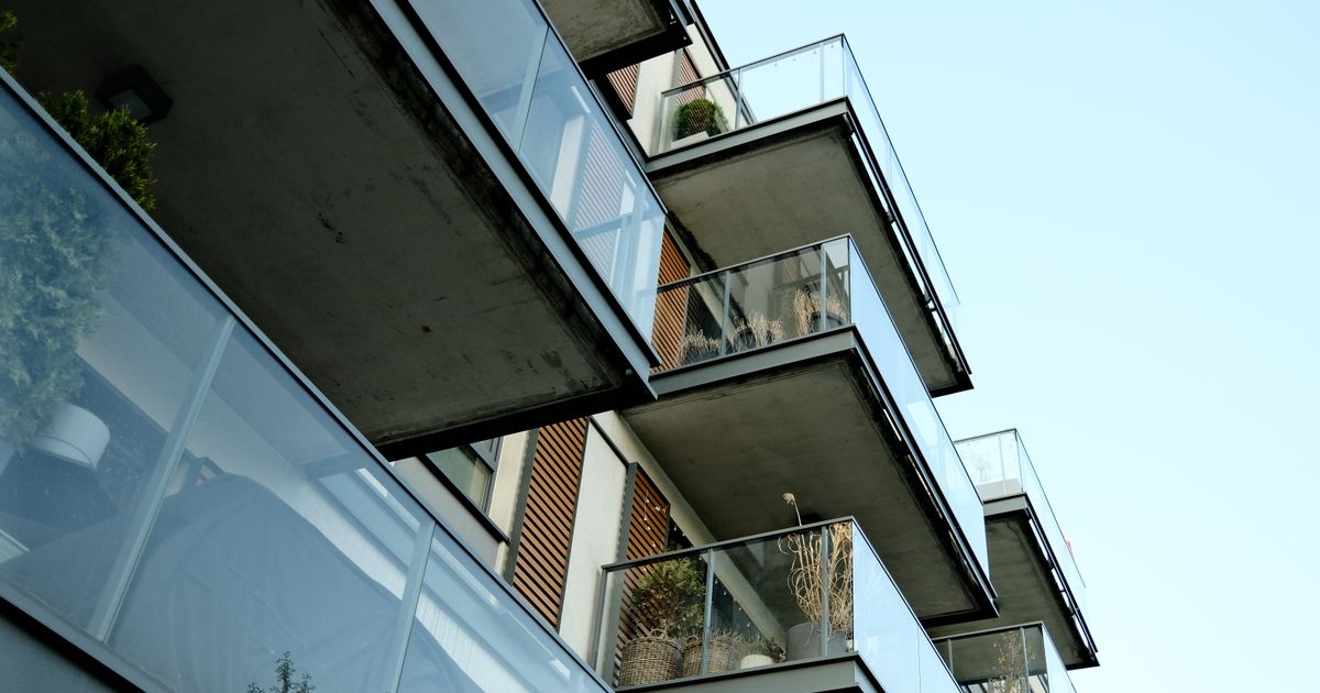 A modern residential building's glass balconies under a clear sky, showcasing contemporary architecture.