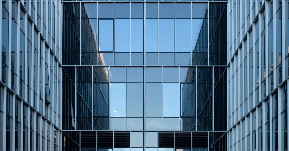 Contemporary building facade with reflective glass windows in an urban environment.
