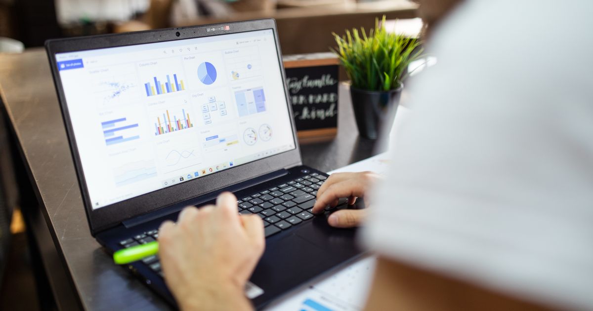 Focused business analysis with charts and graphs on a laptop in a modern office setting.