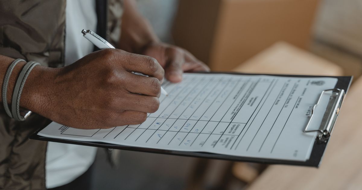 Close-up of person writing on form attached to clipboard, capturing the diligent process.