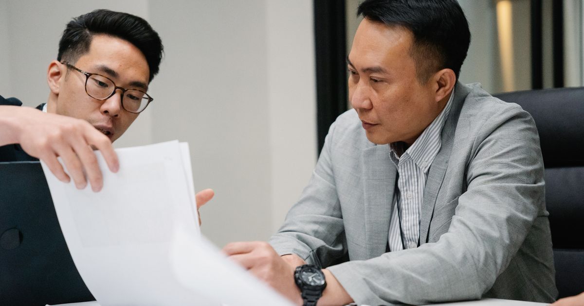 Two professional men engaged in a focused discussion in a contemporary office environment.