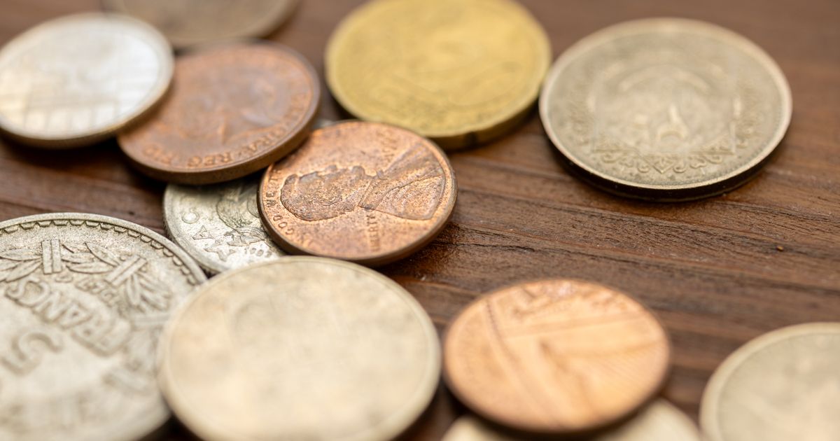 A detailed close-up image showing various vintage coins scattered on a wooden surface, capturing their unique textures and engravings.