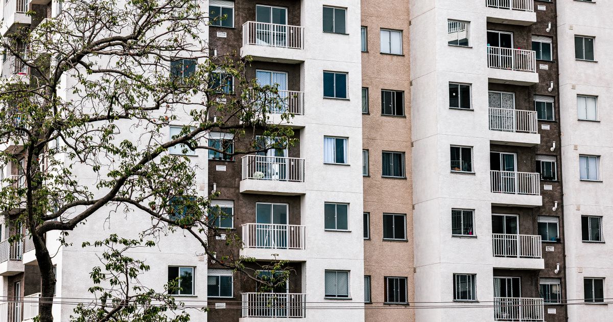 Exterior view of a modern apartment building with balconies and a tree, showcasing urban architecture.